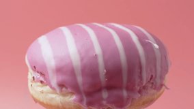 Pink and white donut with a white stripe. The donut rotates on a pink background. - Powered by Shutterstock - Get 15% off with code: PIKWIZARD15