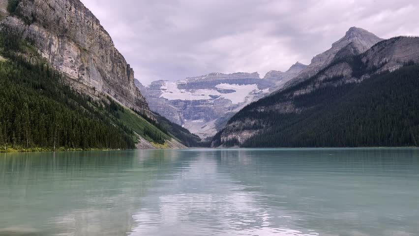 Lake Louise turquoise waters reflecting surrounding majestic mountain peaks and glaciers in Banff National Park, Alberta, Canada. Shot at a low angle from the water surface
