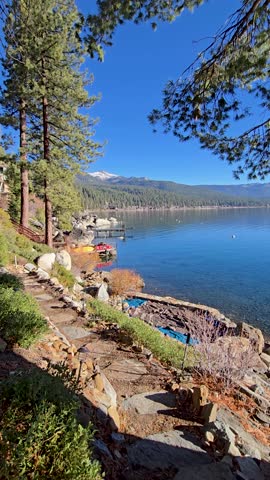 footage of a gorgeous winter landscape at Lake Tahoe with blue lake water, lush green trees and plants and snow capped mountains in Crystal Bay Nevada USA