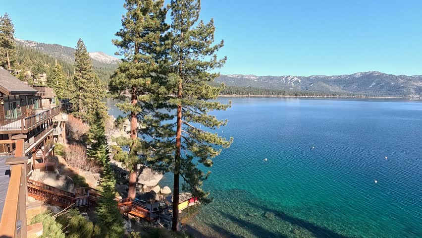 footage of a gorgeous winter landscape at Lake Tahoe with blue lake water, lush green trees and plants and snow capped mountains in Crystal Bay Nevada USA