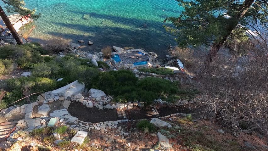footage of a gorgeous winter landscape at Lake Tahoe with blue lake water, lush green trees and plants and snow capped mountains in Crystal Bay Nevada USA