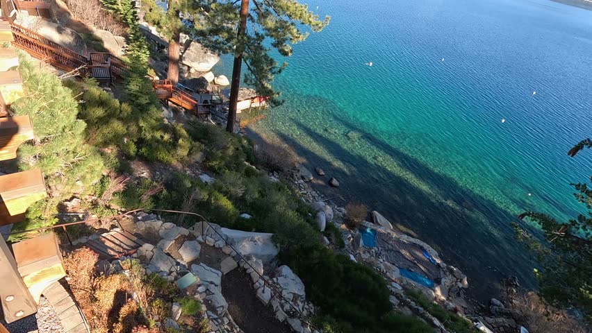 footage of a gorgeous winter landscape at Lake Tahoe with blue lake water, lush green trees and plants and snow capped mountains in Crystal Bay Nevada USA