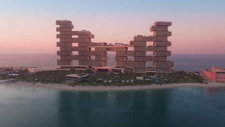 This aerial view showcases the luxurious Atlantis The Royal resort at Palm Jumeirah, enhanced by a stunning sunset, making it ideal for travelers seeking relaxation and adventure