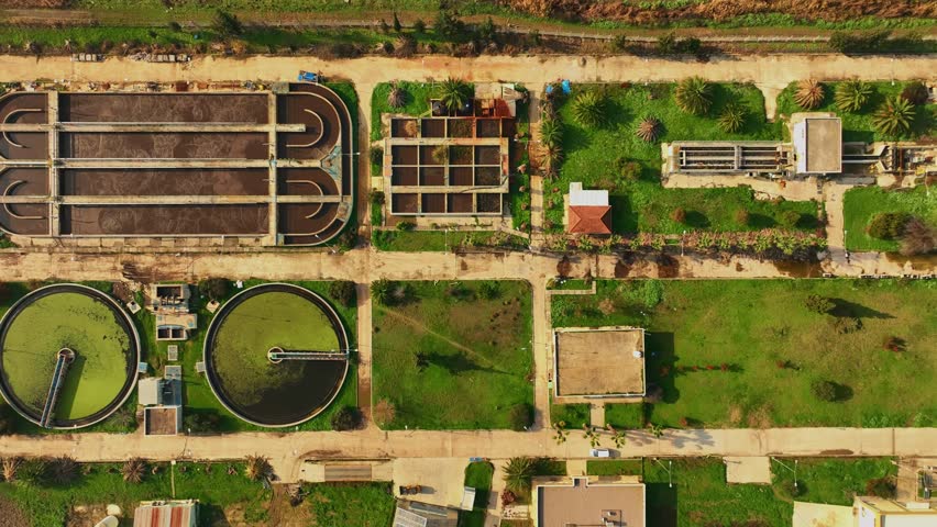 Aerial trucking shot over the huge wastewater treatment plant with beautiful sun rays and flares drone 4k