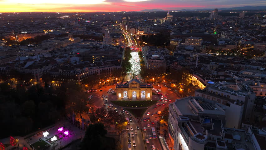 Impressive aerial drone shot beautifully captures iconic Puerta de Alcala in Madrid, breathtaking and vibrant cityscape as the sun sets, highlighting the charming area at dusk, heavy traffic. Spain