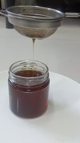 This video shows the process of extracting 100% pure honey, from waste removal to packaging in a white glass bottle, emphasizing its natural purity.