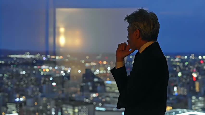 A business person thinking with a city night view in the background