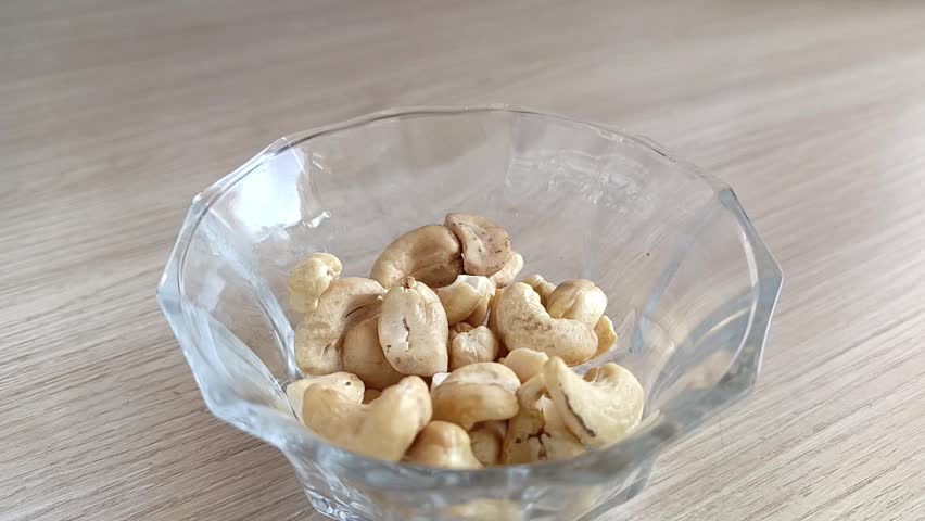 Cashew nuts are poured into a cup on the table. High protein content in nuts. Fresh peeled cashews.