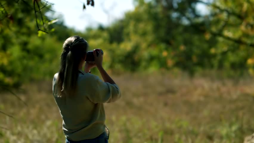 Woman photographer with her camera taking pictures. woman traveler holds professional camera in her hands. Tourist taking picture of amazing landscape on professional photo camera. Travel and hobby