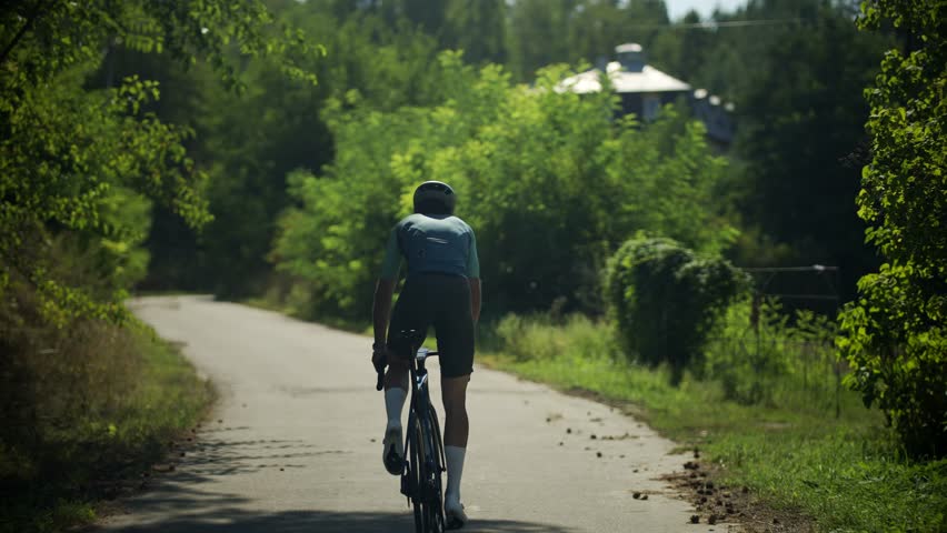 Professional cyclist in sport clothing, protective helmet and mirrored glasses riding bike. Fitness sport activity. Fit strong cyclist preparing for competitions and races. road bicycle racer training Focused Cyclist Navigating Asphalt Route In Rural Area, High Performance Cycling Workout For Endurance And Speed, Sporty Person Pedaling On Modern Racing Bike, Active Lifestyle And Competitive Sports Routine, Summer Training Session On Countryside Road, Controlling Handlebars While Driving Fast, Physical Activity In Natural Environment, Maintaining Fitness Through Intensive Road Exercising, Gear For Professional Sportsmans, Morning Exercise On Countryside Way, Pushing Limits During Long Distance Ride, Cyclist Aerodynamic Position On Bike