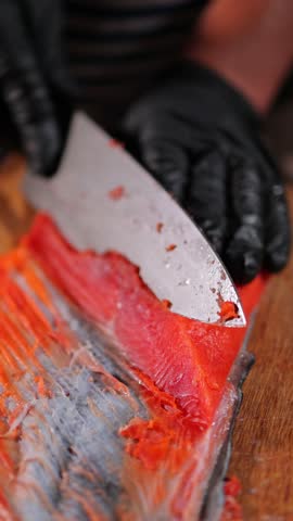 Male hands cutting red salmon fish on a wooden board