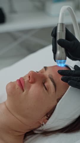 Portrait of a woman who is having a beauty procedure by a beautician. Facial skin care in cosmetology beauty and health of a girl. High quality 4k footage