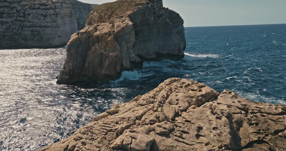 Woman Strolling by the Rocky Shores of Fungus Rock in Malta Gozo Island Captured from Above with Scenic Seascape. High quality 4k footage