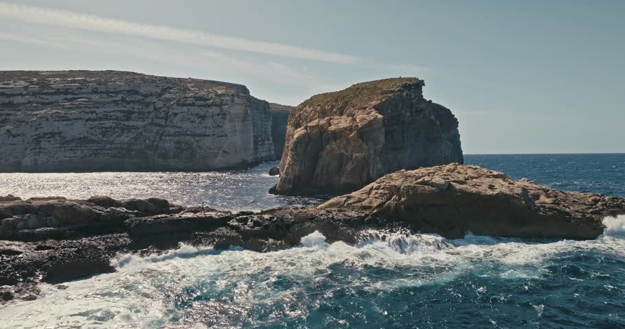 Fungus Rock seascape on the island of Gozo, Malta, aerial view. Sea waves crashing on rocks and stones in the Mediterranean Sea, beautiful nature and tourist landscape. High quality 4k footage
