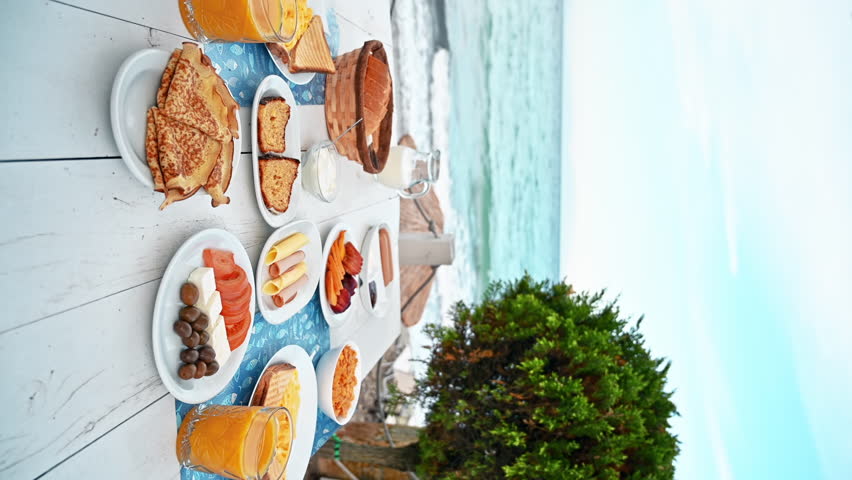 Table full of dishes with food, breakfast on the Aegean sea coast in Greece. Vertical view
