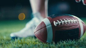 Close-up of an American football player wearing gloves, holding a ball on a grassy field under bright stadium lights at night - Powered by Shutterstock - Get 15% off with code: PIKWIZARD15