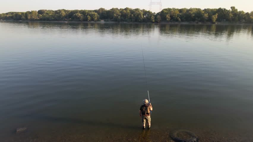 Enjoying a peaceful fishing experience by the serene riverbank during sunset