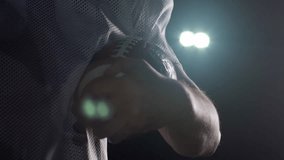 Portrait of a Caucasian male American football player wearing a team uniform, pads and a helmet, holding a football in his hands, raising head and looking to camera, slow motion - Powered by Shutterstock - Get 15% off with code: PIKWIZARD15