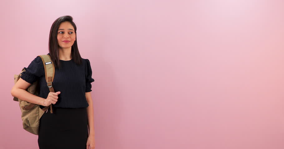 Attractive smiling Asian student girl looking at camera waving hand gesture hi hello, greeting or saying goodbye, welcoming, isolated over pink background.