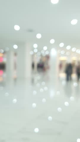 Vertical blurred video of a bustling mall with people walking by. Perfect for adding a modern, dynamic touch to your projects. Ideal as a lively background or overlay for social media and more