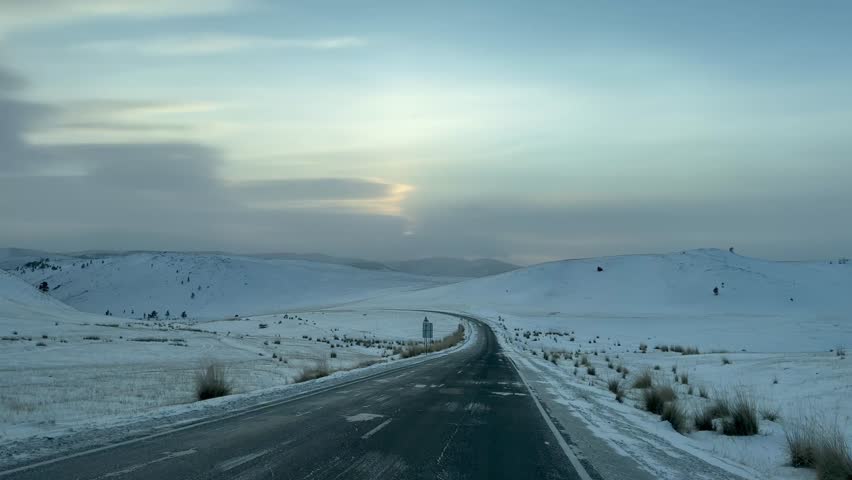 Video of winter snowy road on Tazheran steppe with snow-covered hills at sunset. Road to Baikal Lake coast. Scenic winter landscape. Natural background. Winter car traveling and outdoors