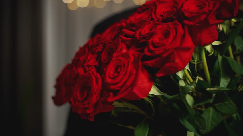 blurred silhouette happy face handsome man hands holding bouquet of red roses scarlet flowers. Romantic in love guy carries Valentine