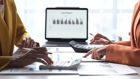 Two women are working on a spreadsheet together. One of them is pointing at a number on the screen - Powered by Shutterstock - Get 15% off with code: PIKWIZARD15