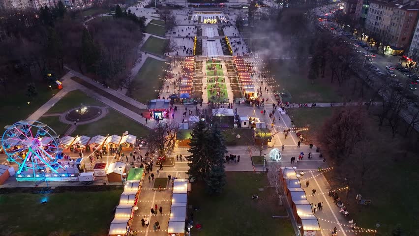 Night aerial view of the capital of Bulgaria Sofia. Architectural and iconic buildings in the city center. Christmas market with a Ferris wheel and an amusement park. Sunset, sunrise