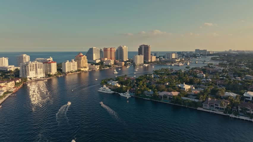 Florida’s international coastal waterway in Fort Lauderdale from an aerial drone with hotels, condos, yachts, sailboats, blue skies, canals, life, and activity sunny summer day cinematic epic