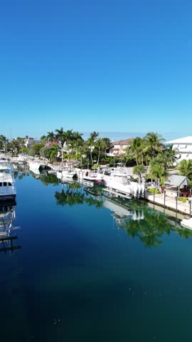 Aerial rising drone view to reveal the sea, beach, and blue waters on the other side of waterfront houses.
