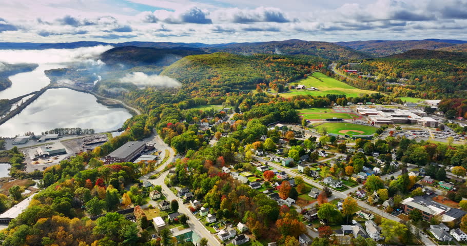Flight above the beautiful scenery of Vermont, New England, USA. Amazing autumn nature near the lake. Dramatic clouds hang over the rocks at backdrop.