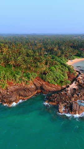 Distancing from the beautiful shore with bare rocks and tropical forest. Coastline of the Indian Ocean at Sri Lanka. Vertical video.