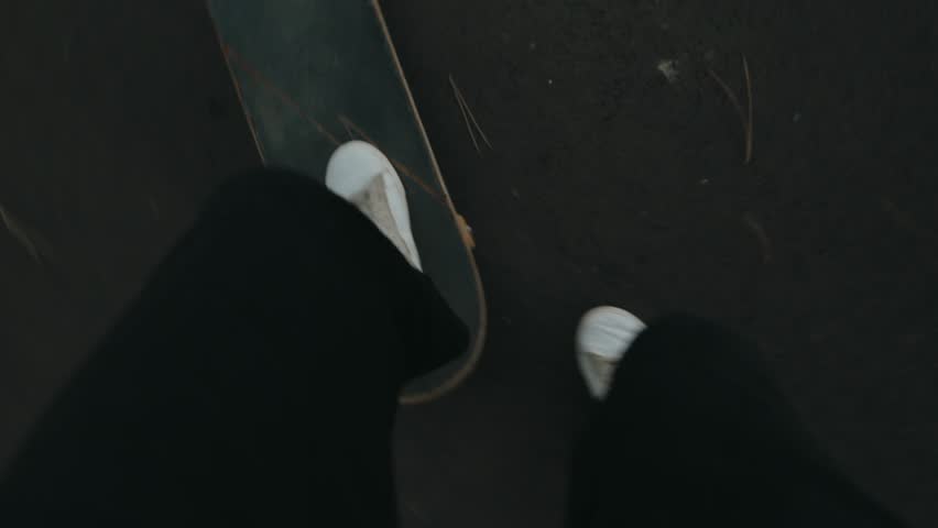 Point of view shot of a skateboarder riding down an empty road. Slow motion shot of white shoes on a skateboard. POV urban street skating.