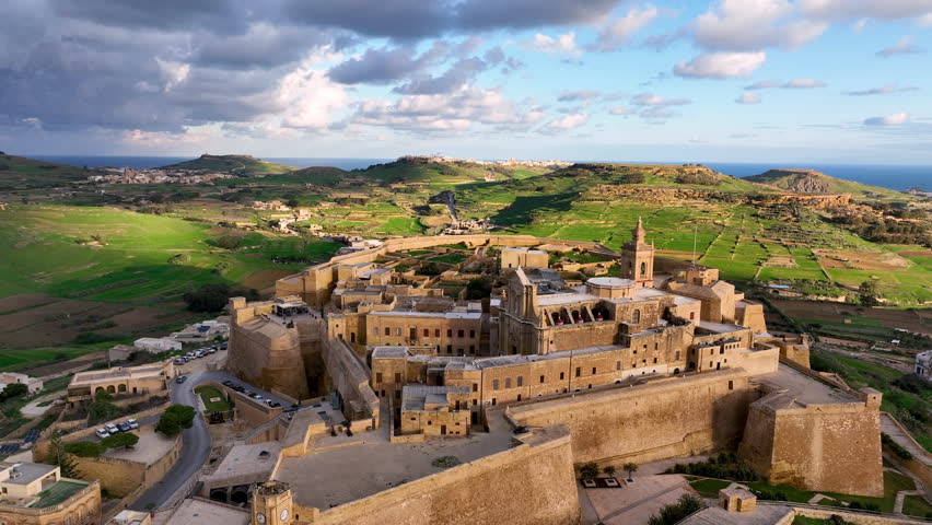 4k Aerial view of Historic fort, Citadel Ruins on cliff overlooking valley at sunset with lush greenery in the background. island Gozo. Malta