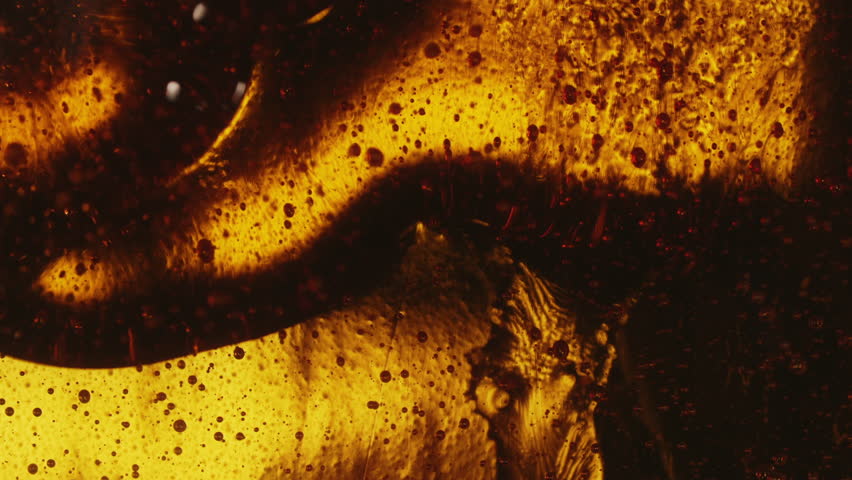 Close-up abstract pouring oil liquid, caramel or fresh honey with lot of air bubbles, seamless dripping sweet syrup flows, thick honey dripping, golden oil flowing, sweet food concept