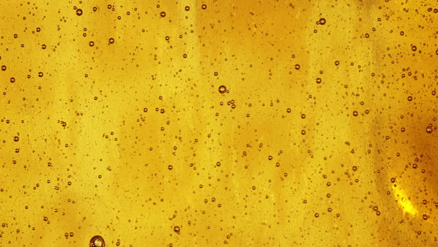 Close-up slow motion shot of pouring yellow caramel or fresh honey with air bubbles, seamless dripping sweet liquid syrup drip flows, thick organic honey dripping, golden caramel sauce flowing