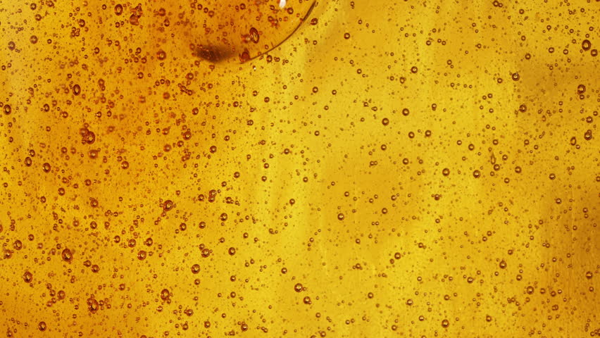 Close-up slow motion shot of pouring yellow caramel or fresh honey with air bubbles, seamless dripping sweet liquid syrup drip flows, thick organic honey dripping, golden caramel sauce flowing