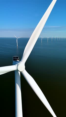 Witness a stunning array of wind turbines standing tall against a clear blue sky. The renewable energy sources gracefully blend with the picturesque landscape in the Netherlands