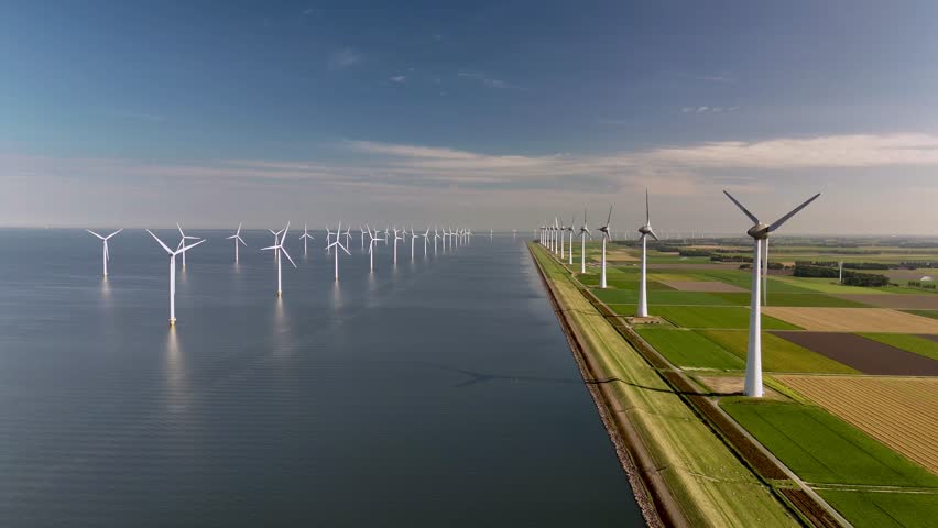A stunning view of massive windmill turbines situated along the tranquil waters of the Netherlands. These renewable energy giants spin gracefully, contributing to sustainable power.