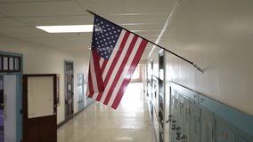 A vacant school hallway features bright lighting and blue lockers on one side. An American flag hangs overhead symbolizing education and patriotism in the environment. - Powered by Shutterstock - Get 15% off with code: PIKWIZARD15