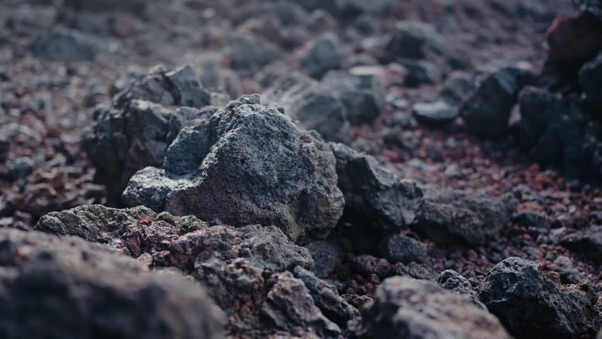 Detailed close-up of volcanic rocks scattered across a rugged and rocky landscape. Perfect for backgrounds, geological themes, and nature studies. Background texture from lava stones