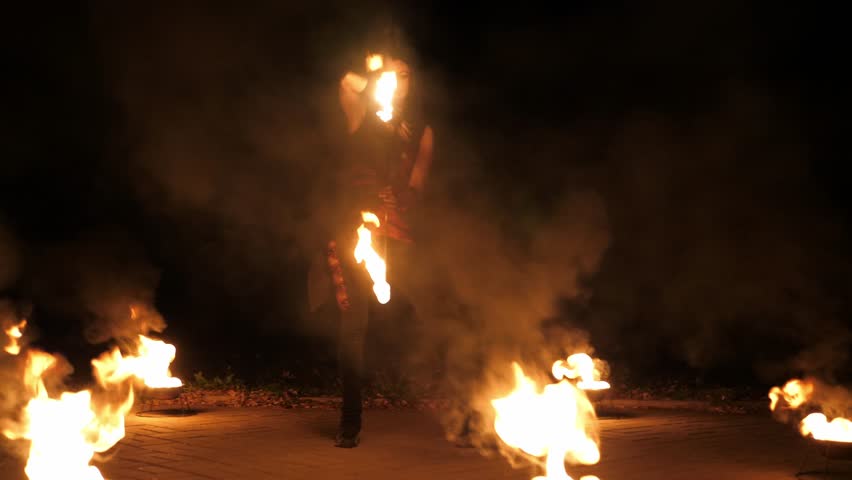 Circus performance with fire outdoors at night, street art festival, a woman performs with burning torches. An amazing fire show. A fire show.