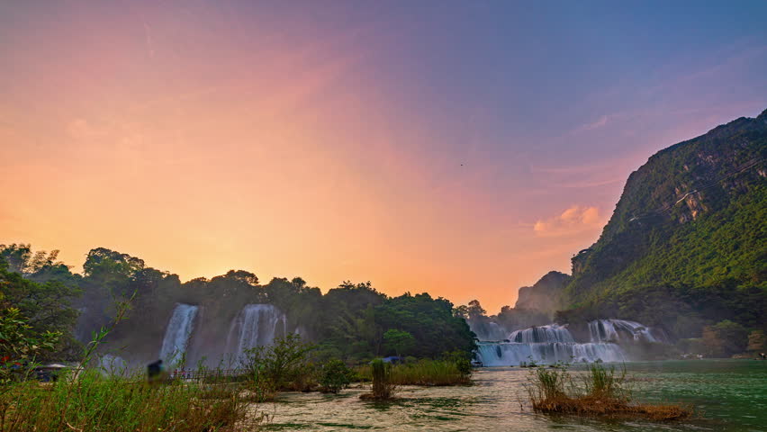 A serene twilight scene featuring cascading the great Ban Gioc Waterfall surrounded by lush greenery. the sky transitions from day to dusk, creating a peaceful and atmospheric moment in nature.