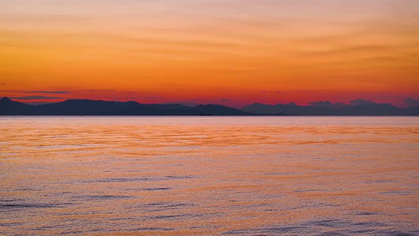 Aerial flight or captains boat POV over the calm ocean into the golden sunset with segulls