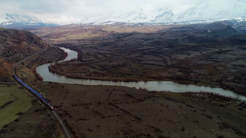 In autumn, a narrow-gauge railway station in a small town sees trains near the river. Trains run on tracks, carrying cargo or passengers, powered by locomotives or motors.