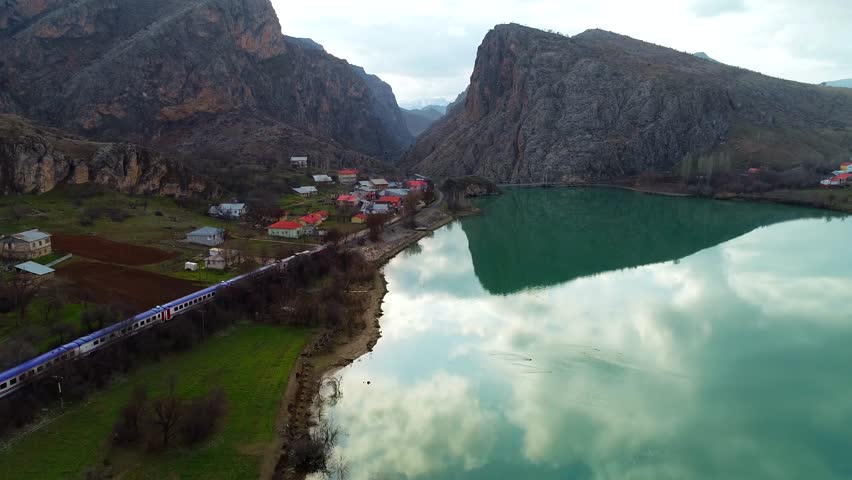 In autumn, a narrow-gauge railway station in a small town sees trains near the river. Trains run on tracks, carrying cargo or passengers, powered by locomotives or motors.