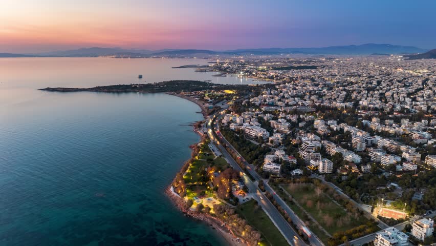 Aerial hyper lapse view of the illuminated Athens Riviera coast in Voula and Glyfada during dusk, Greece