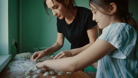 Mother and daughter working together shaping dumplings on wooden surface. Female teaching child proper technique while forming dumplings. Lady and girl enjoying time preparing homemade dumplings as - Powered by Shutterstock - Get 15% off with code: PIKWIZARD15