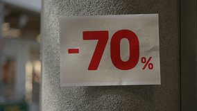 Close-up of a person's hand attaching a bold red seventy percent discount sign to a gray store column. The bright promotional poster highlights massive discounts during a sale event, emphasizing Black - Powered by Shutterstock - Get 15% off with code: PIKWIZARD15