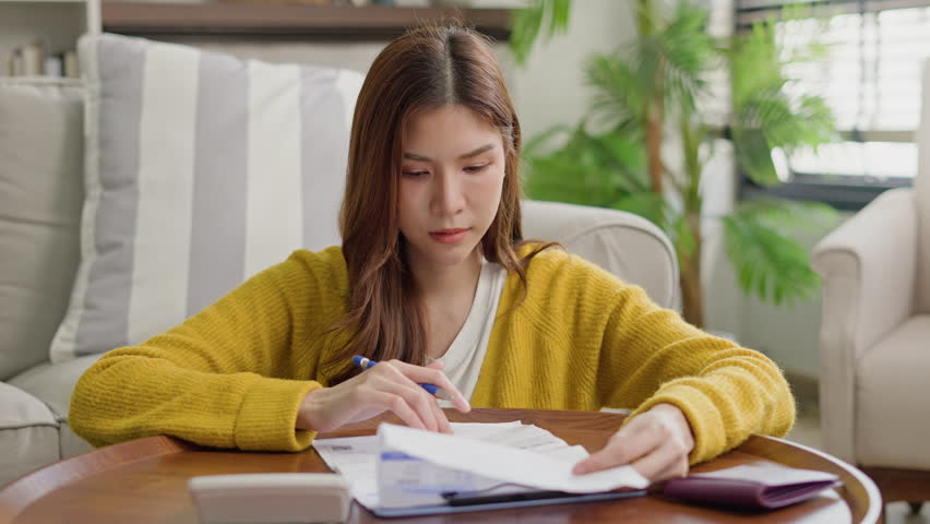 asian young woman stress and worry by calculate expense from invoice or bill not able money to pay mortgage.frustrated female reading paper report from bank.debt,loan,bankruptcy,Bad financial concept